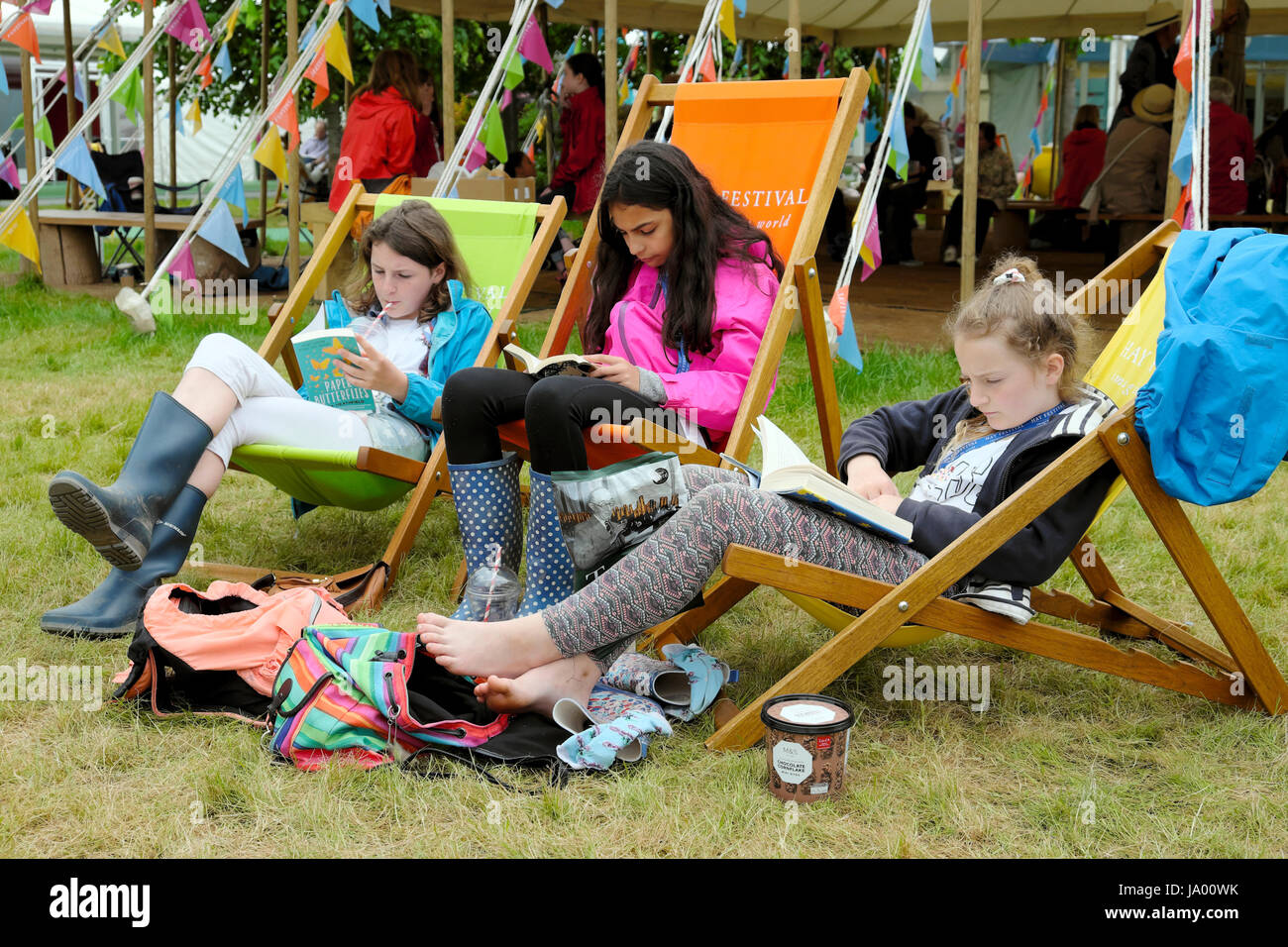 Eine Gruppe Teens Mädchen Freunde Lesen von Büchern sitzen auf Liegestühlen im Hay Festival, Hay-on-Wye, Wales UK KATHY DEWITT Stockfoto