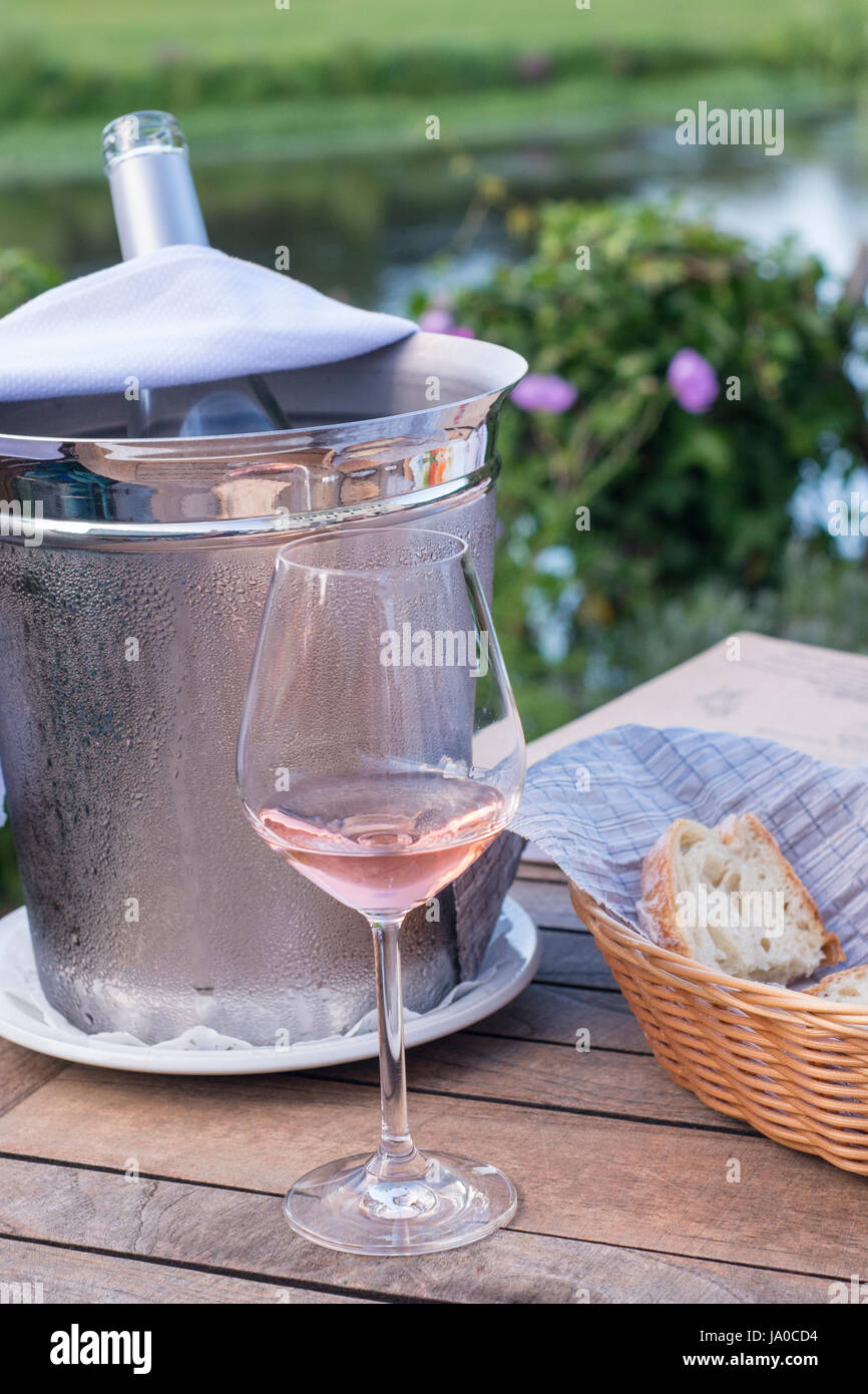 Am frühen Abend Szene von einem Glas Rose, Brot in einen Korb und ein Weinkühler, die während des Sommers in den frühen Abend in Frankreich. Stockfoto