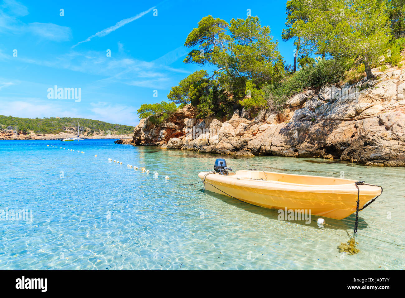 Gelbe Boot ankern am idyllischen Strand Cala Portinatx und Cliff rockt mit Pinien im Hintergrund die Insel Ibiza, Spanien Stockfoto