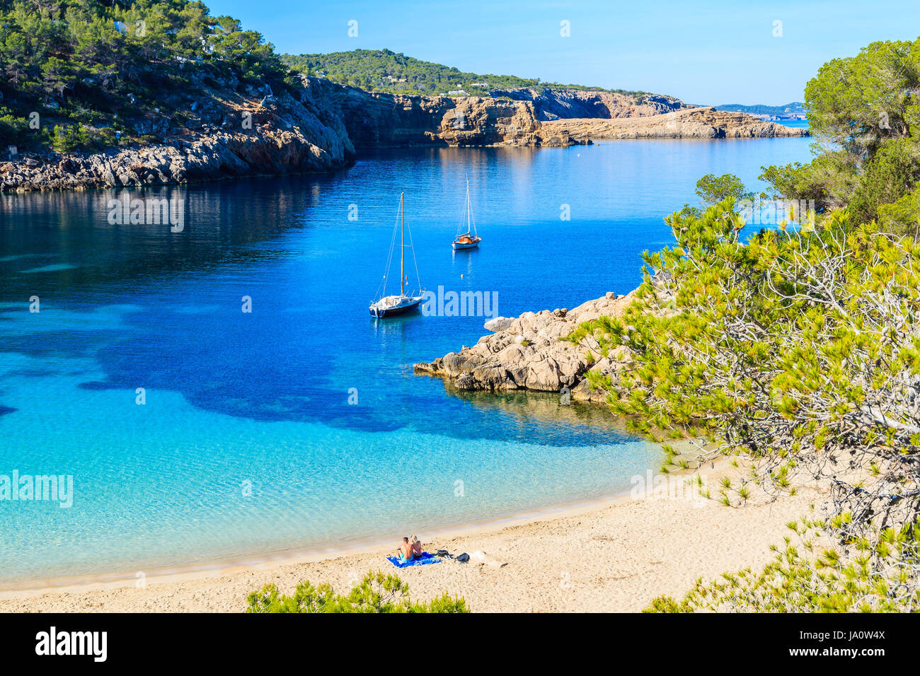 Paar Unidentifed Leute Sonnenbaden am schönen Strand von Cala Salada berühmt für seine Azure kristallklares Meerwasser, Insel Ibiza, Spanien Stockfoto