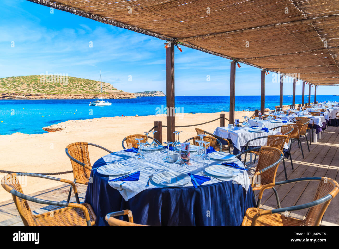 CALA COMTE BAY, Insel IBIZA - 17. Mai 2017: Tabellen auf der schattigen Terrasse des Luxus Küsten-Restaurant am Strand von Cala Comte Sie berauscht genießen Stockfoto