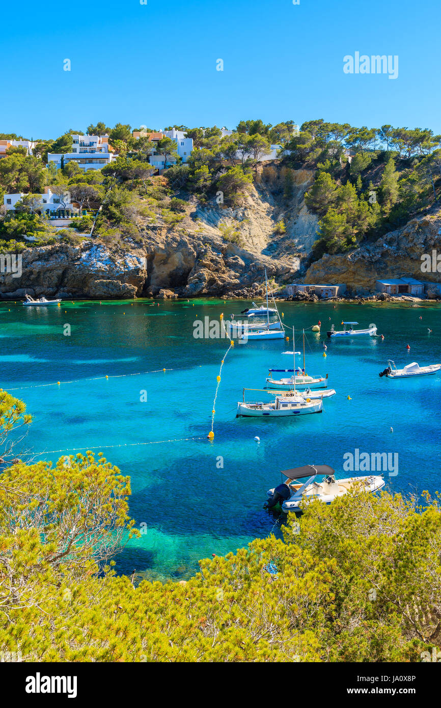 Angel- und Segelboote am blauen Meer Wasser in der Bucht Cala Vadella, Ibiza Insel, Spanien Stockfoto