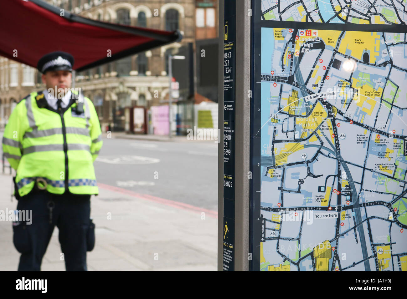 Ein Polizist steht hinter einem London Lokalinformationen Führer der Borough Markt Bereich Szene von die tödlichen Messerstechereien durch mutmaßliche Islamisten Credit: Amer Ghazzal/Alamy Live-Nachrichten Stockfoto