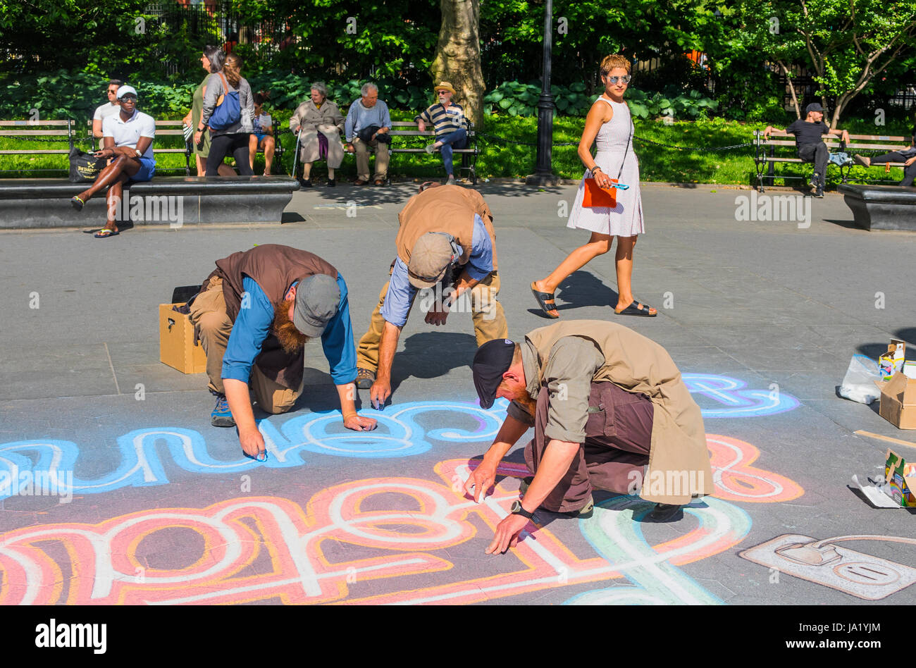 Drei im mittleren Alter Männer mit Bärten und Kappen zeichnen eine Nachricht auf dem Bürgersteig im Washington Square Park in Greenwich Village in New York City Stockfoto