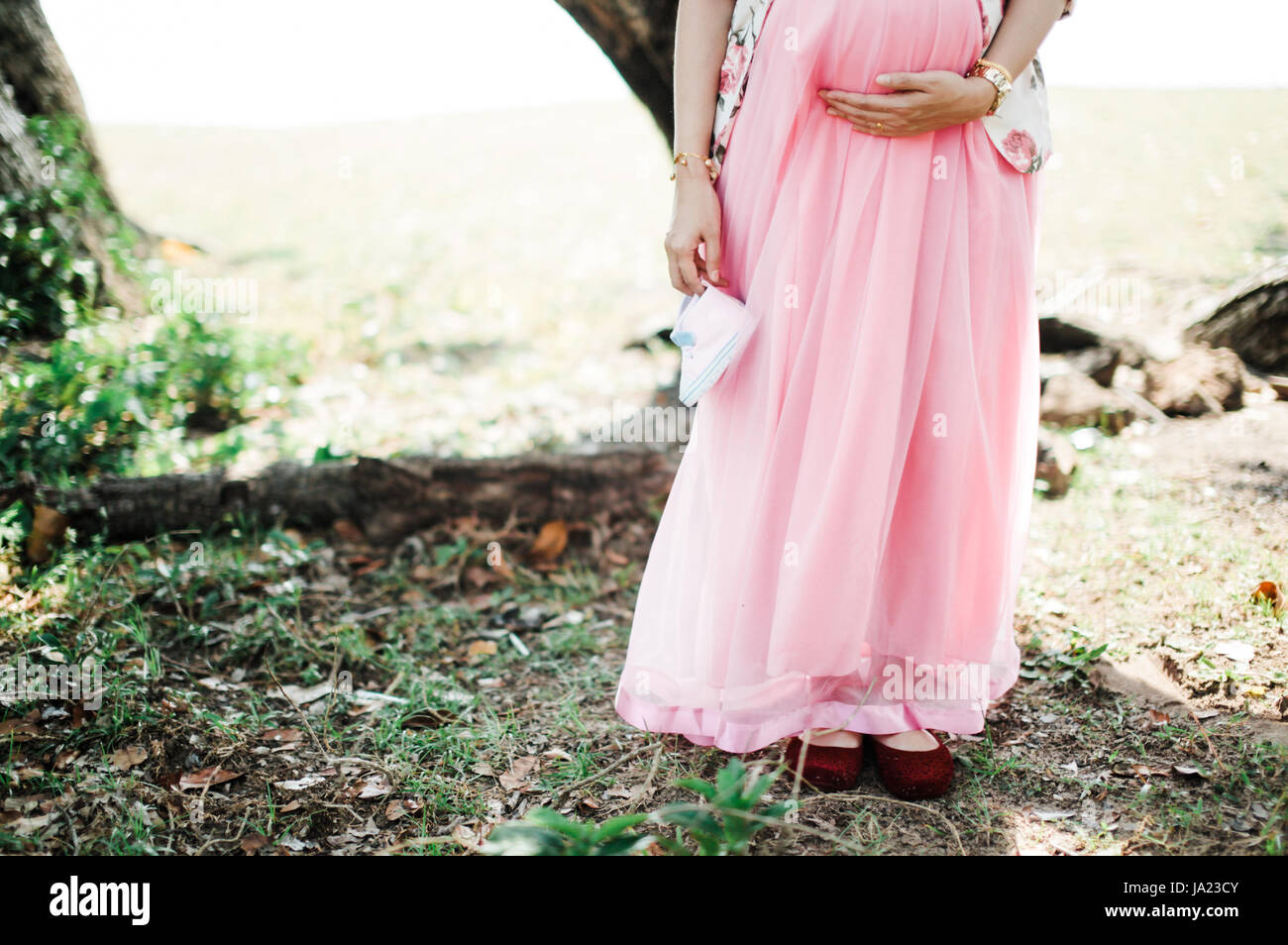 Eine Mutter halten seinen Bauch und halten Babyschuhe bei Outdoor-location Stockfoto