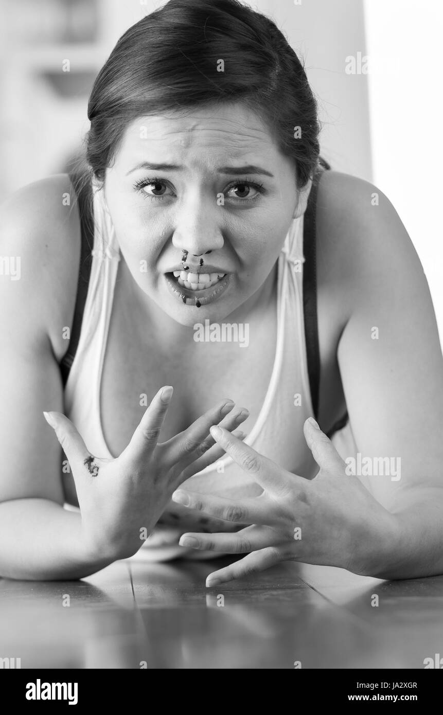 Schöne Frau Nasenbluten, Frau blutet aus der Nase auf Holzfußboden, schwarz-weiß-Effekt Stockfoto