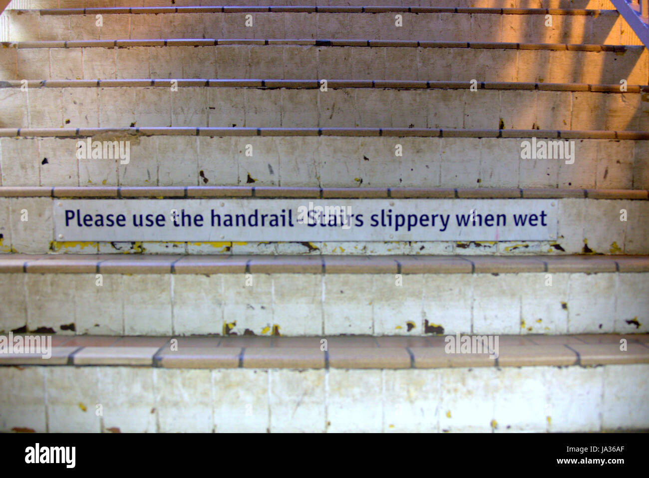Bitte benutzen Sie Handläufe Treppe rutschig bei Nässe Zeichen auf Treppenhaus Stockfoto
