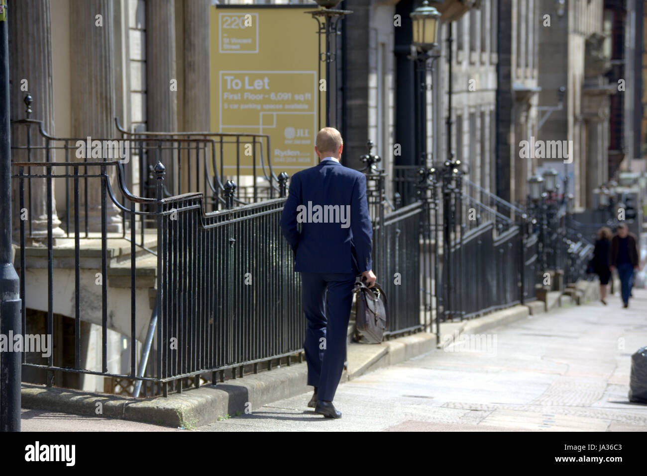 Geschäftsmann im Anzug zu Fuß auf der Straße Glasgow Stockfoto