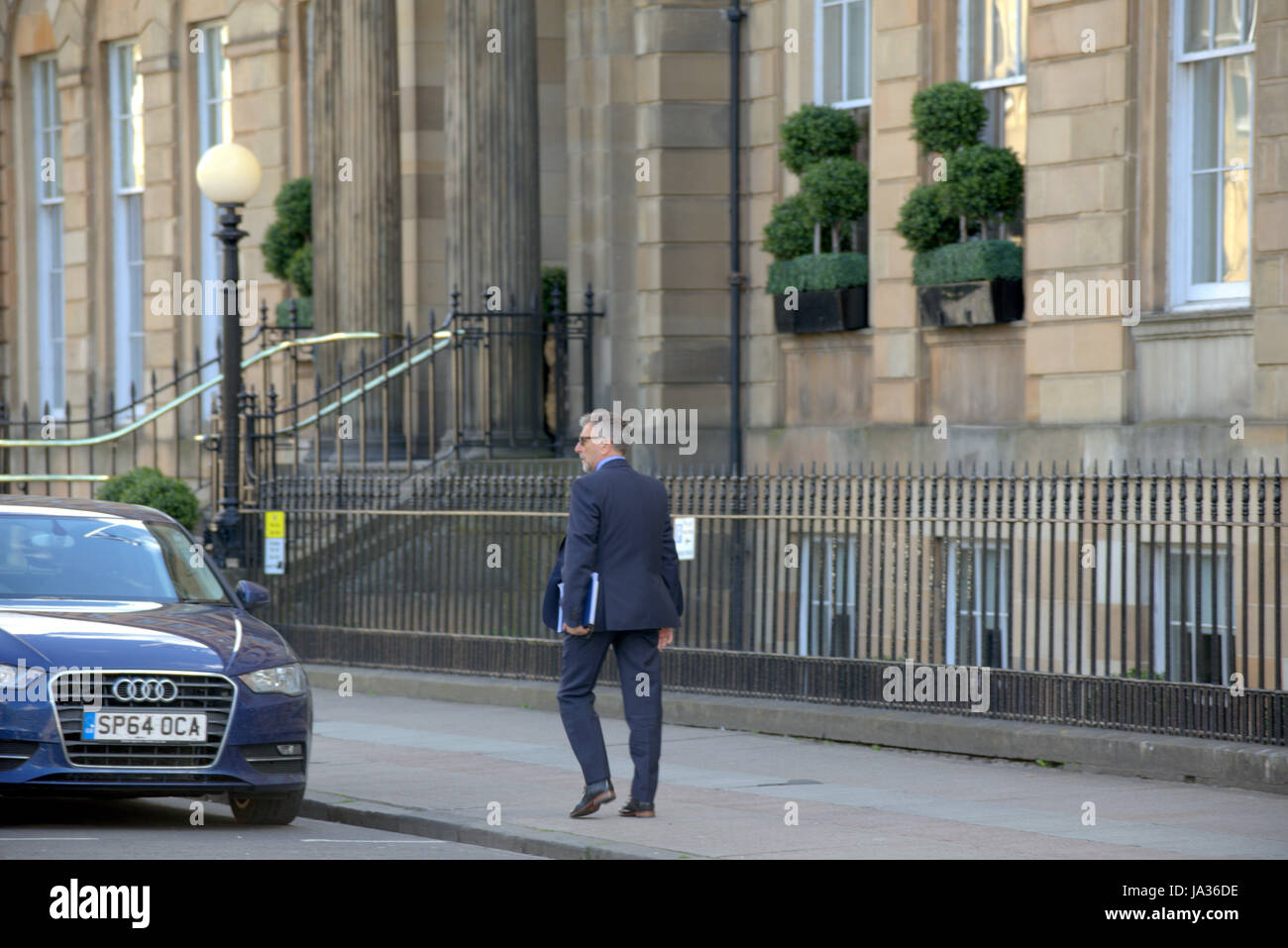 Geschäftsmann im Anzug zu Fuß auf der Straße Glasgow Stockfoto