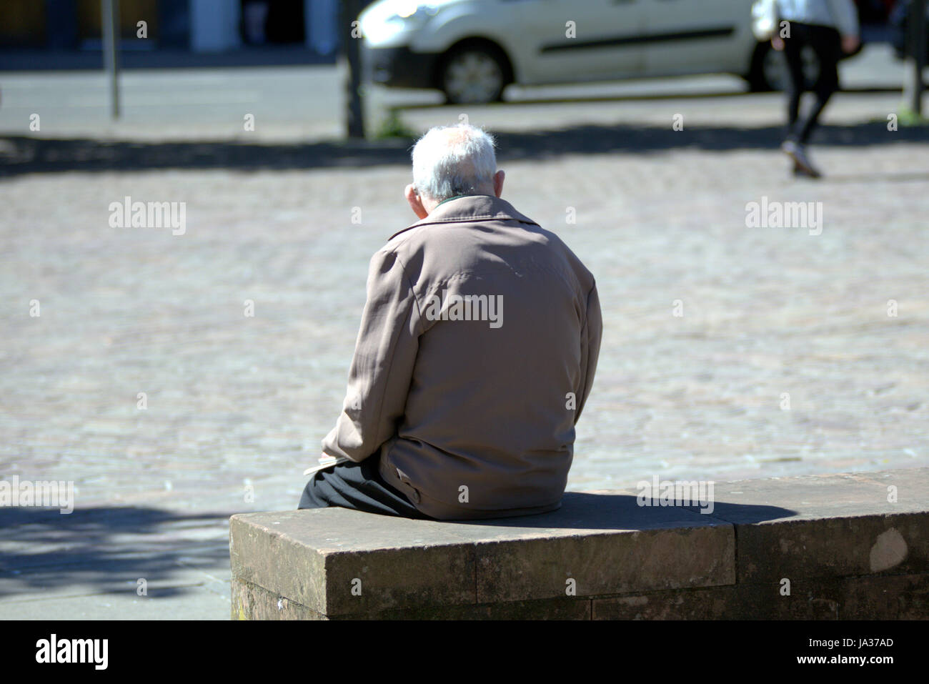 sitzen auf einer Bank hinter alter Mann betrachtet man jungen Menschen betrachtet Stockfoto