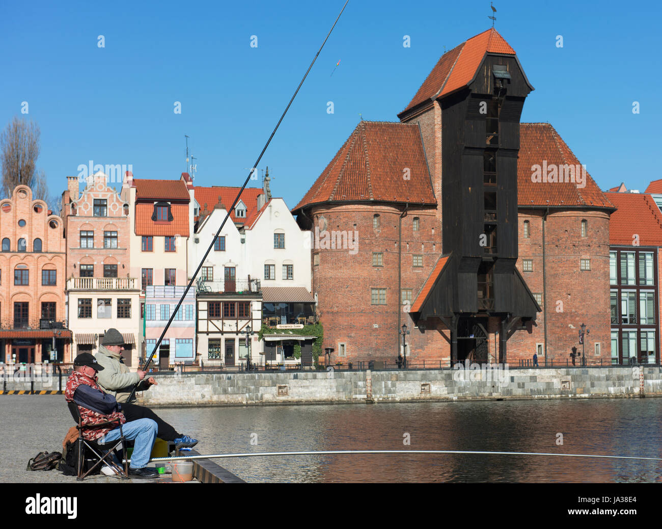 Männer angeln auf der Mottlau in der Danziger Altstadt mit der mittelalterlichen Kran und National Maritime Museum im Hintergrund. Stockfoto