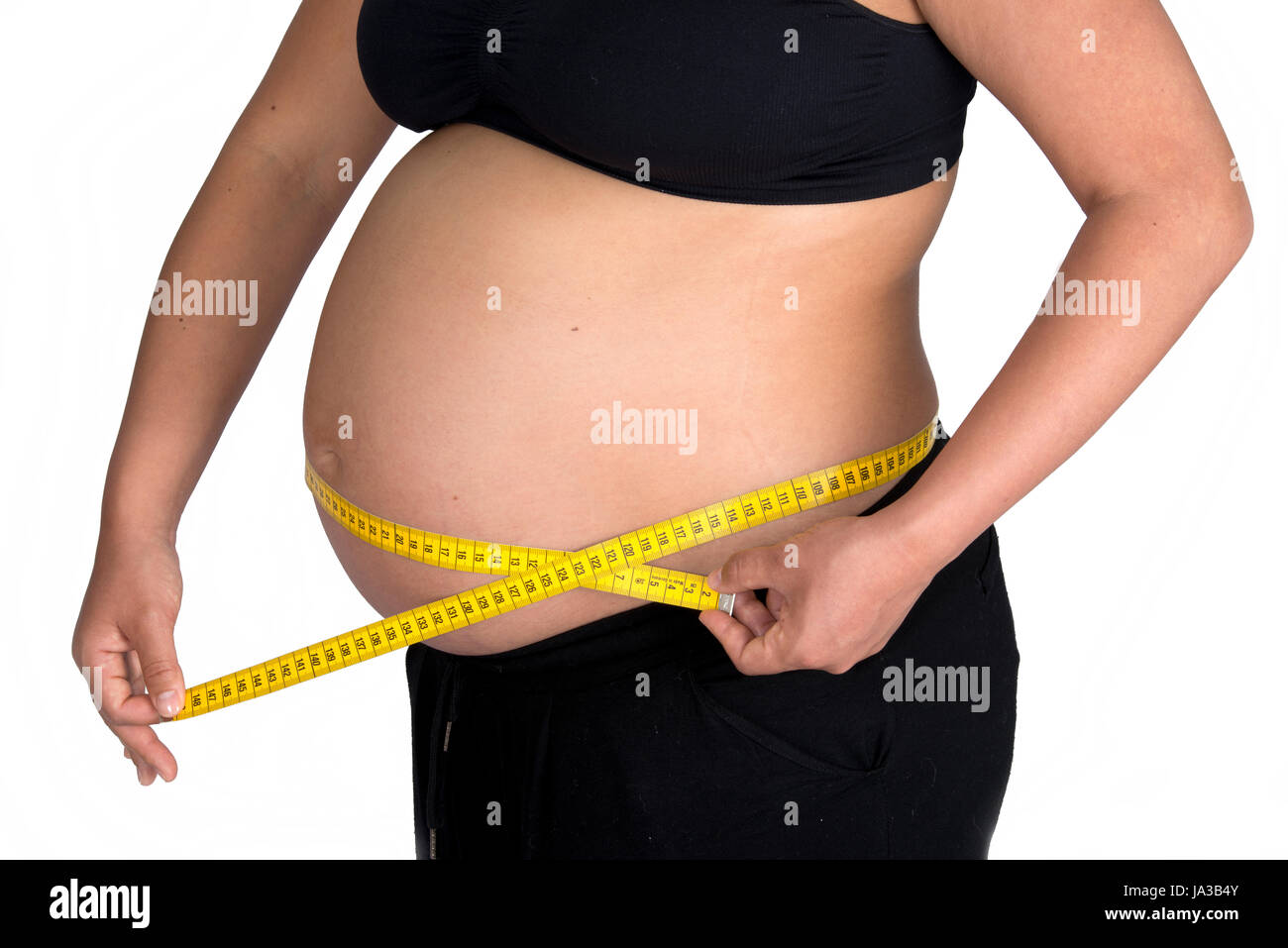 Eine schwangere Frau nutzt ein Stück Maßband um zu nehmen die Maße von  ihrer Schwangerschaft Beule Stockfotografie - Alamy