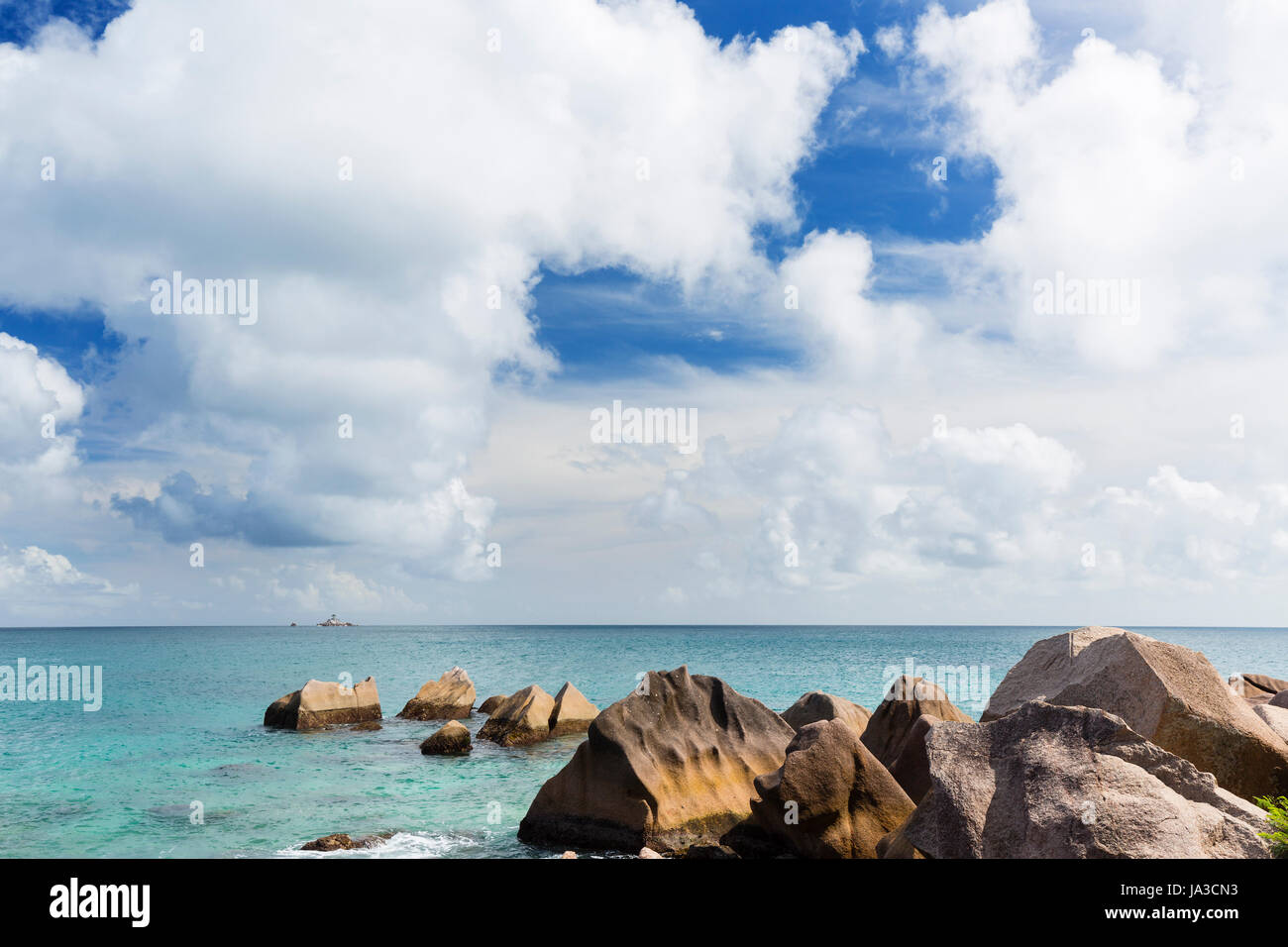 Felsigen Nordküste von La Digue, Seychellen mit einer winzigen Insel im Hintergrund Stockfoto