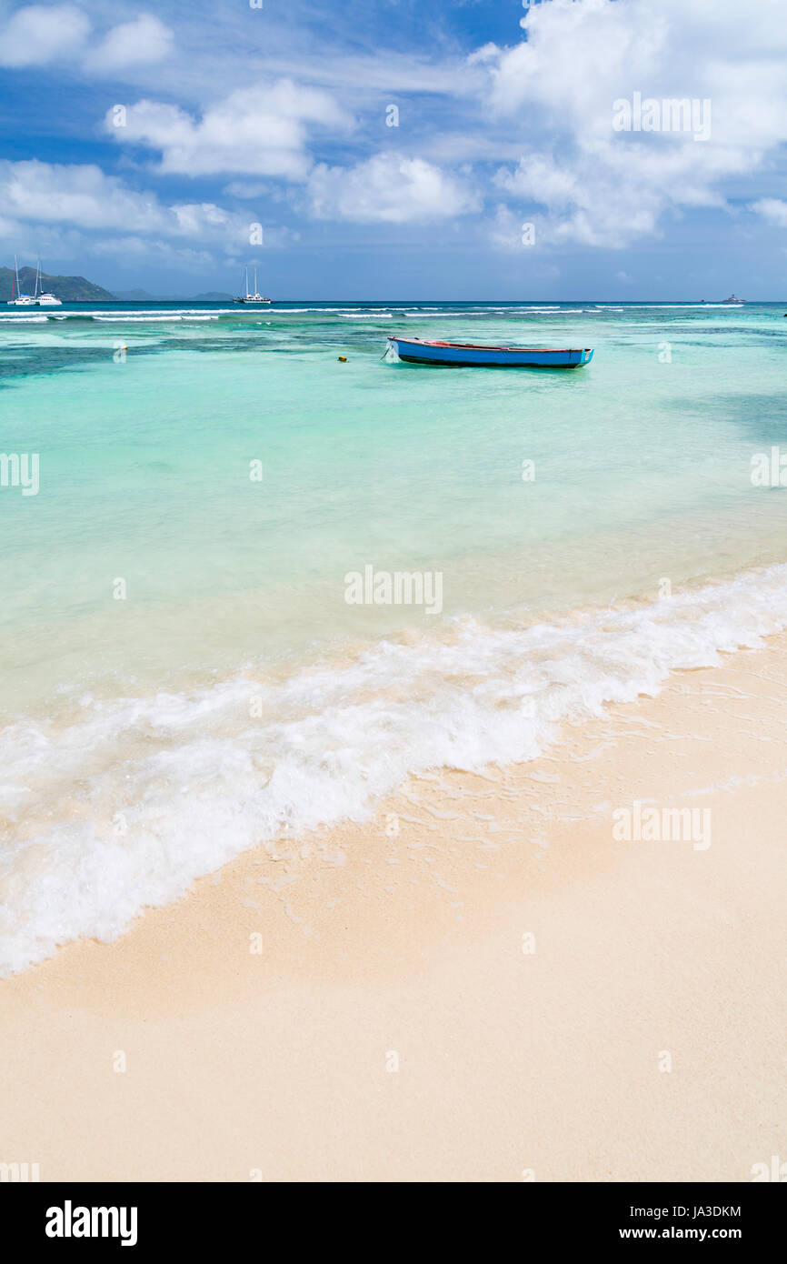 Ein kleines blaues Boot in einer Lagune in La Digue, Seychellen mit Blick auf Praslin Stockfoto