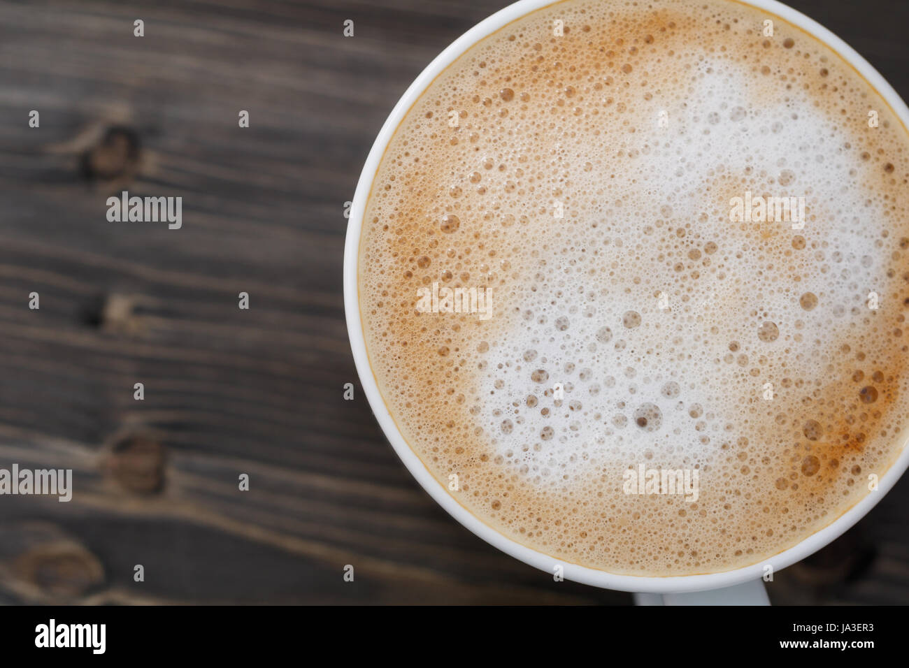 Draufsicht auf eine weiße Tasse Cappuccino auf einem schwarzen Holztisch. Nahaufnahme, Makro erschossen. Kopieren Sie Raum. Stockfoto