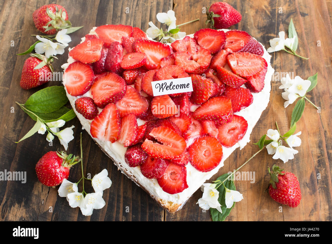 Welcome Card mit Erdbeeren Käsekuchen in Herzform auf rustikalen hölzernen Hintergrund. Stockfoto