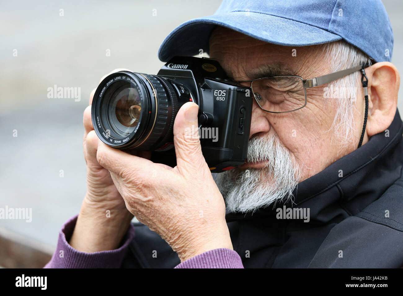 Kopf und Schultern Schuss der Rentner tragen Stil Basecap durch Canon EOS Kamera suchen Stockfoto