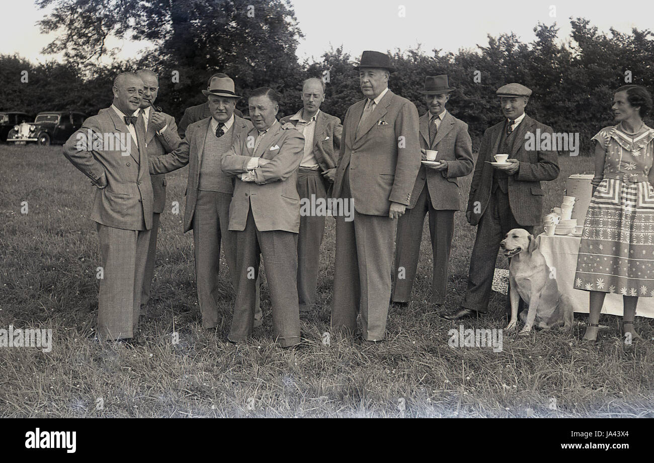 1950er-Jahren, historische. Gruppe von gut gekleideten Herren stehen zusammen mit einer Tasse Tee auf einer Fete oder Outdoor-Event. Stockfoto