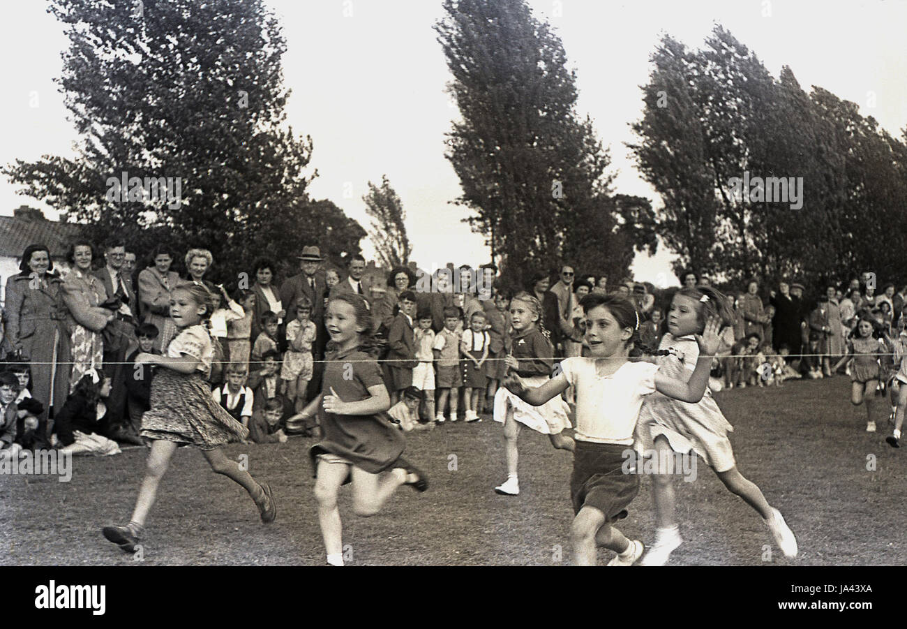 1950er-Jahren, historische, junge Mädchen das finishing Seil in der 60 Yard Dash an einer Grundschule zu treffen Sport Tag, England, UK. Stockfoto