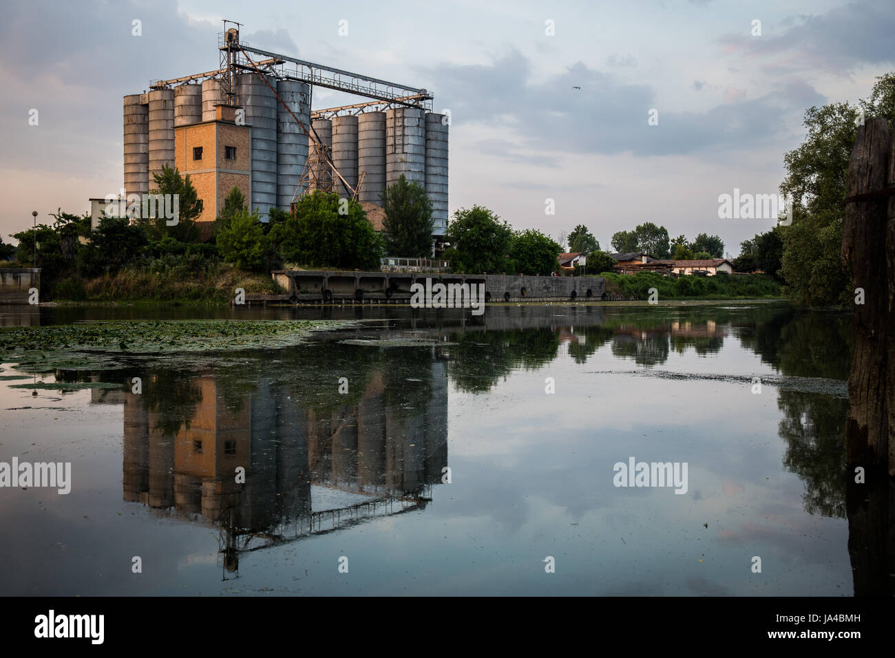 Alte Fabrik mit Silos und Reflexion auf dem Wasser - Landschaft Stockfoto