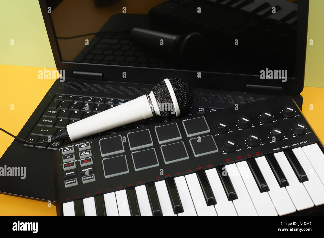 Musikinstrument - MIDI-Keyboard, Laptop und Vokal-Mikrofon für Karaoke auf einem Flavovirent Hintergrund. Stockfoto