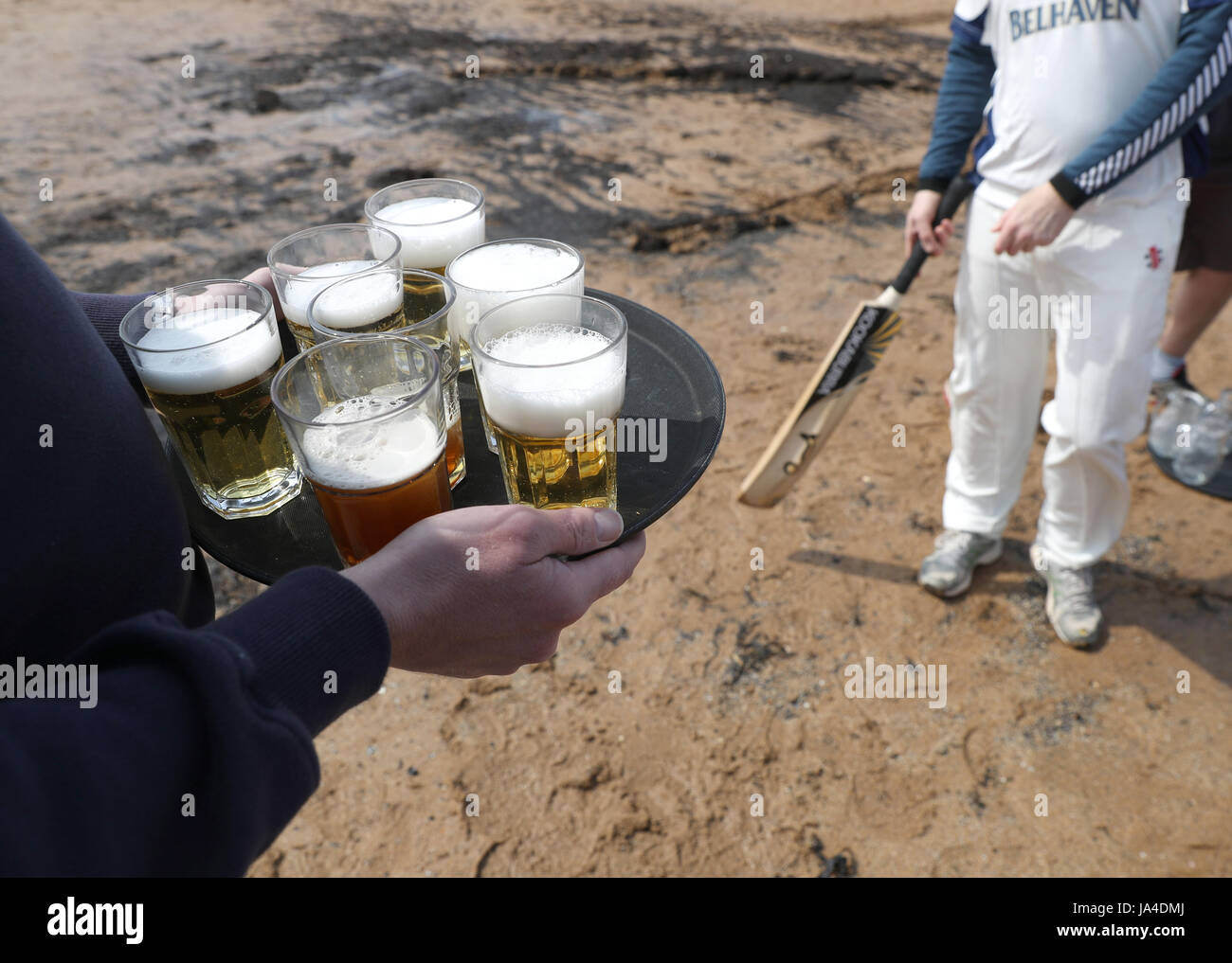 Erfrischungen werden beim Cricket-Spiel am Strand in Elie zwischen dem Cricket-Team Ship Inn in Elie, Fife und dem exzentrischen Flamingos CC verteilt. Das Ship Inn ist der einzige Pub in Großbritannien, der ein Cricket-Team mit einem Platz am Strand hat. Die Saison des Ship Inn CC läuft von Mai bis September, wobei die Daten der Spiele von der Gezeiten abhängen. Sie spielen gegen eine Kombination aus regelmäßiger Opposition aus Schottland und Touring-Teams aus der ganzen Welt. Jeder Batsman, der eine sechs trifft, die im Biergarten des Ship Inn landet, gewinnt seine Höhe im Bier und jeder nicht spielende Zuschauer, der eine sechs im Biergarten A fängt Stockfoto