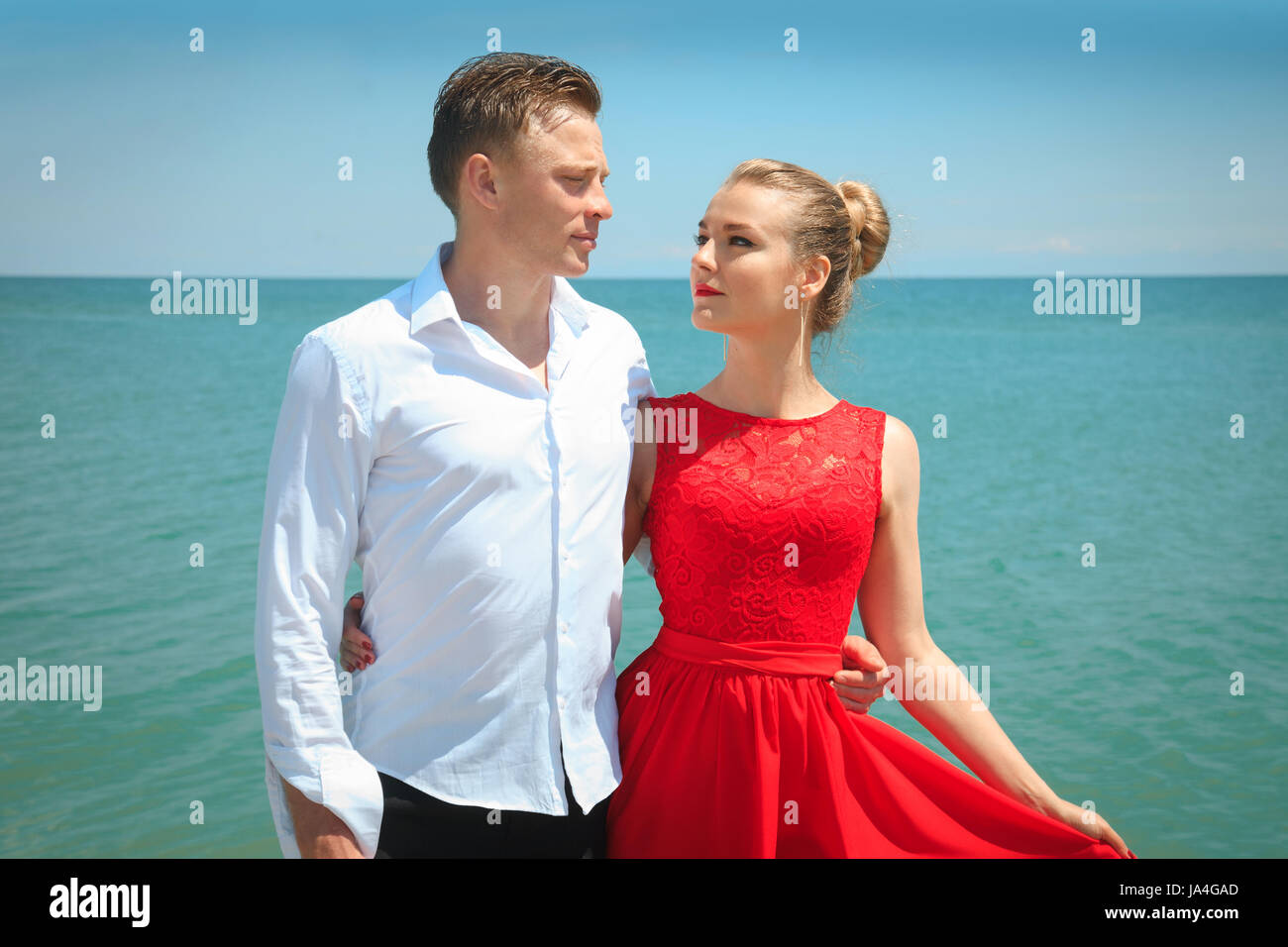 Mann umarmt eine Frau Delicatly posiert mit ihr am Meer. Portrait über ein schönes paar im Urlaub. Stockfoto