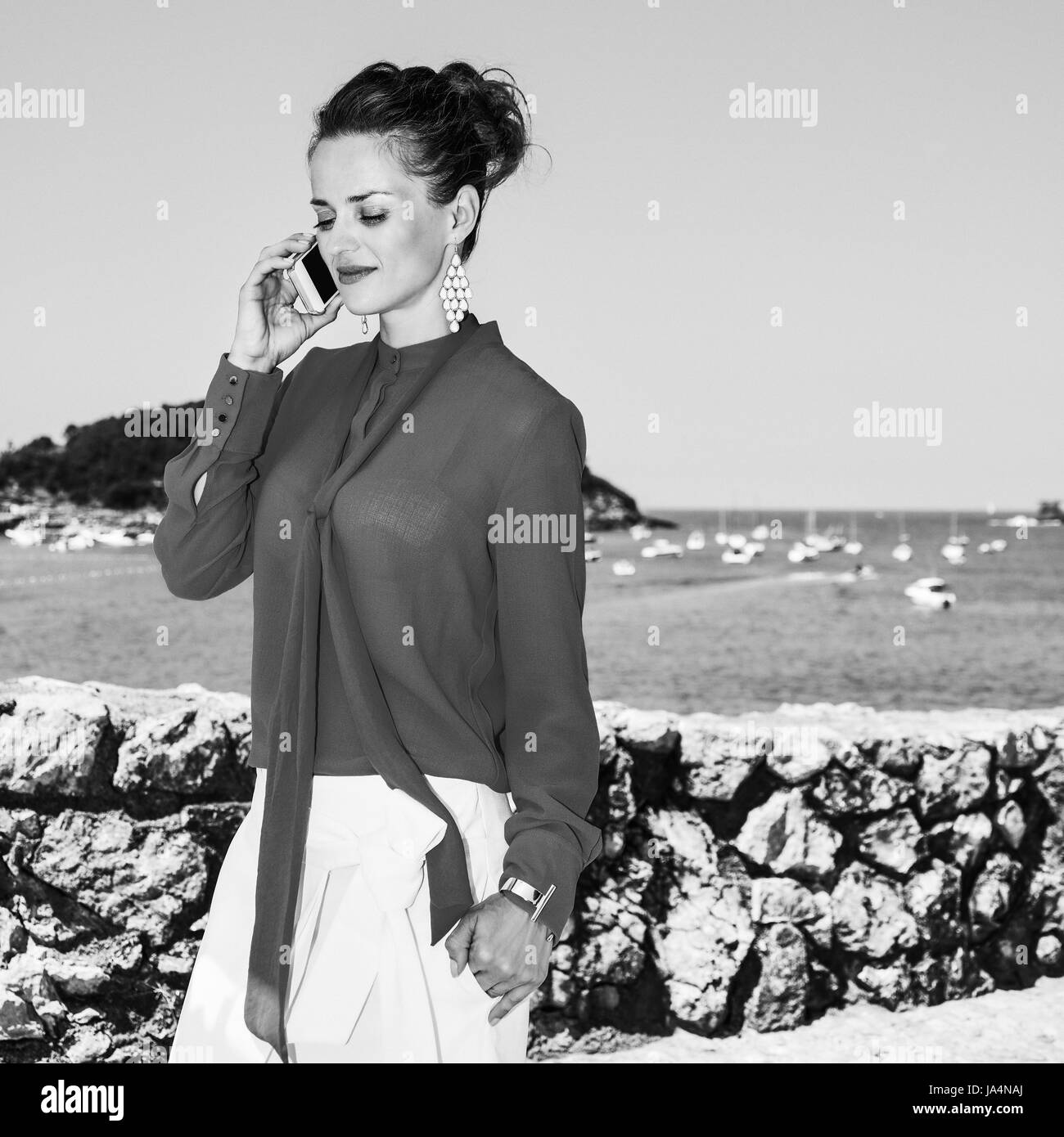 Luxus Wochenende Rückzug. lächelnde Frau der moderne Reisende in rote Bluse stand vor der schönen Kulisse mit Blick auf Lagune mit Yachten in Dono Stockfoto