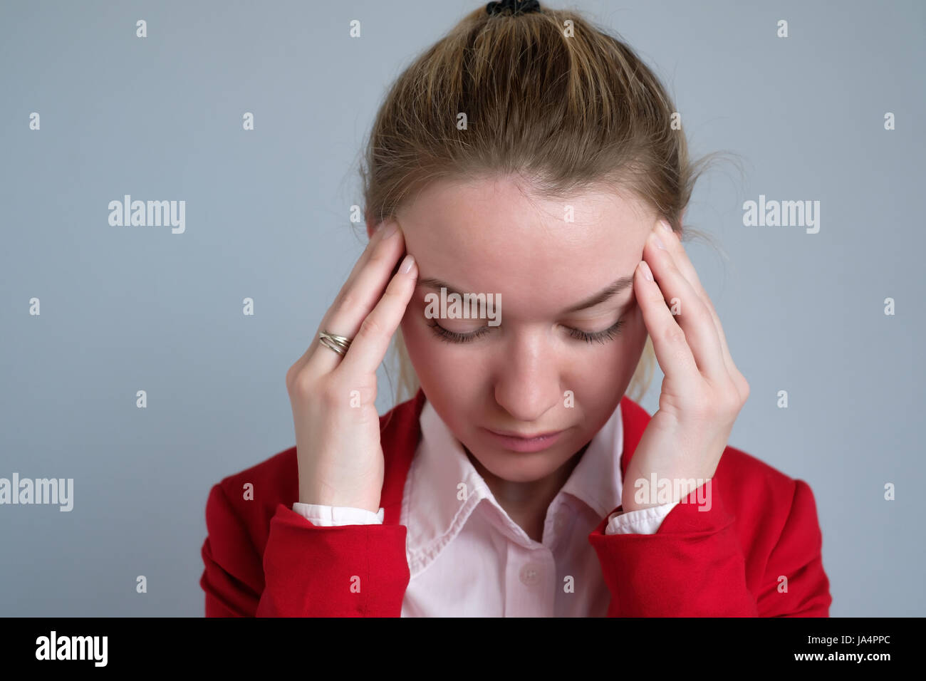 Porträt einer Geschäftsfrau in einer roten Jacke leidet unter Kopfschmerzen. Stockfoto