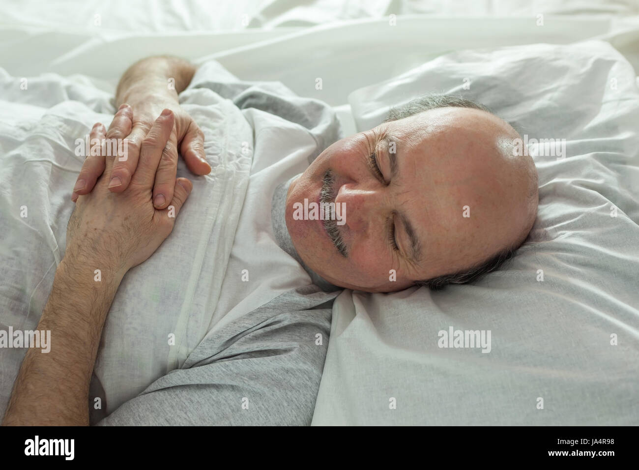 Der ältere Mann schläft schnell, von einer weißen Schneedecke bedeckt. Gesunder Schlaf in der Nacht Stockfoto