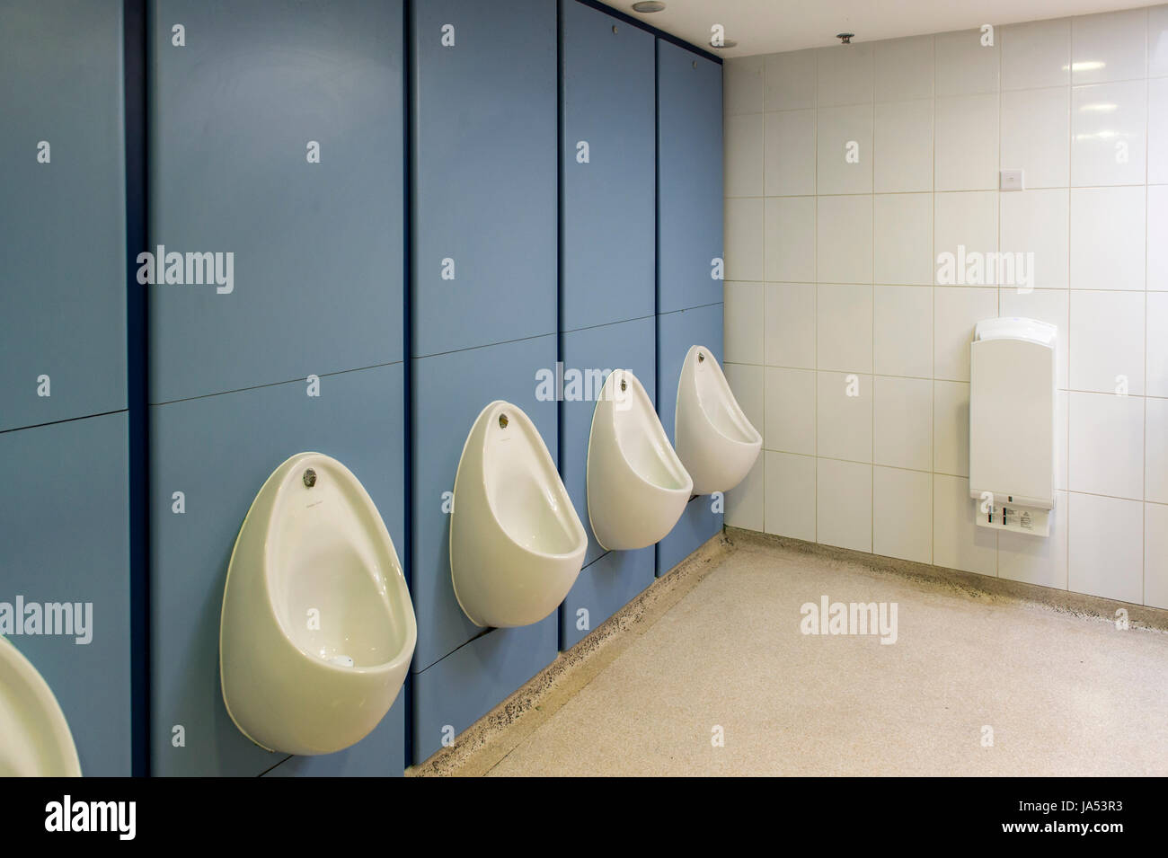 Interieur einer Herren-Toilette in einem Einkaufszentrum mit Urinalen und einem Handtrockner. Stockfoto