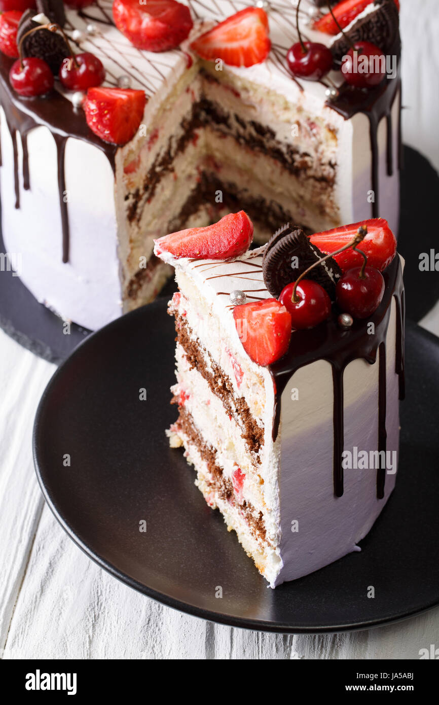 in Scheiben geschnittene Mousse Torte mit frischen Erdbeeren und Kirschen, dekoriert mit Schokolade Closeup. vertikale Stockfoto