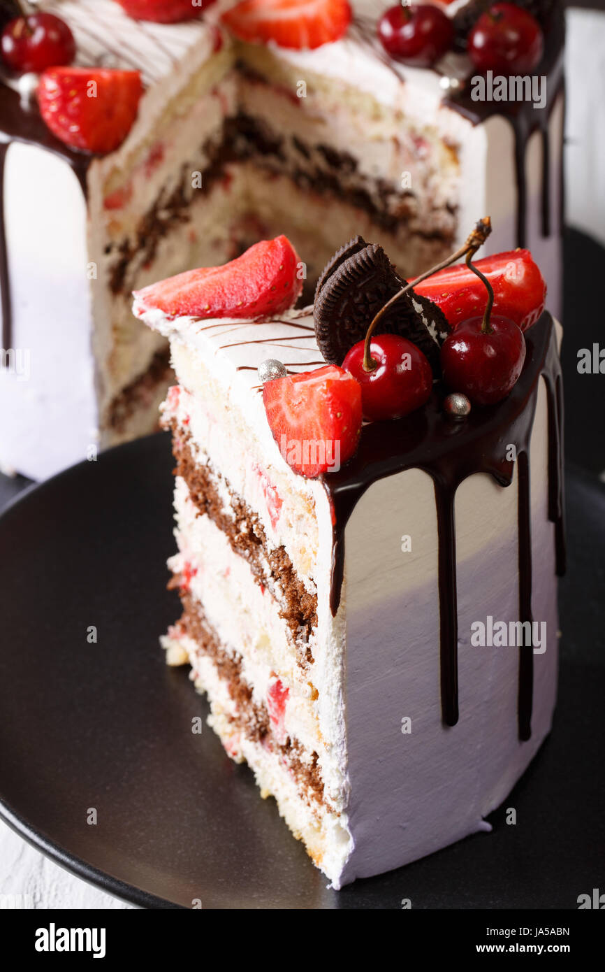 Stück Kuchen mit frischen Erdbeeren und Kirschen und Schokolade Nahaufnahme auf einer Platte. vertikale Stockfoto
