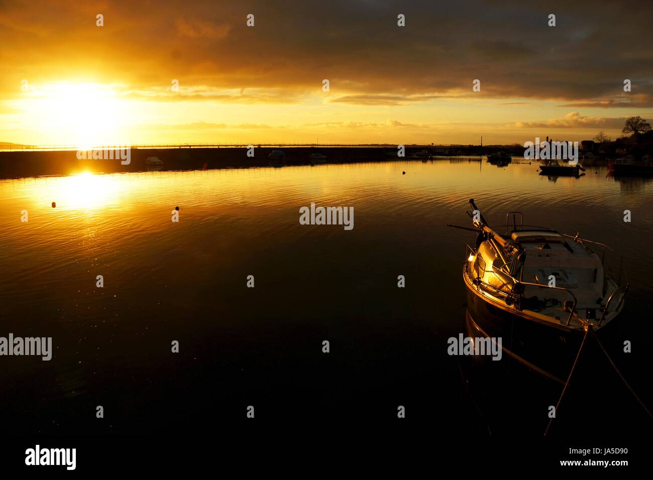 Ein Boot im Hafen von Cockwood, Devon, UK eingefangen in goldenes Licht des Sonnenaufgangs Stockfoto