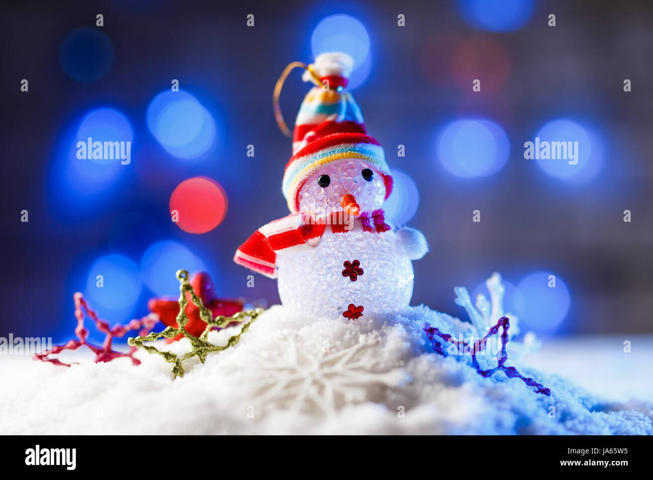 Weihnachtsschmuck im Schnee mit blauer Hintergrundbeleuchtung. Stockfoto