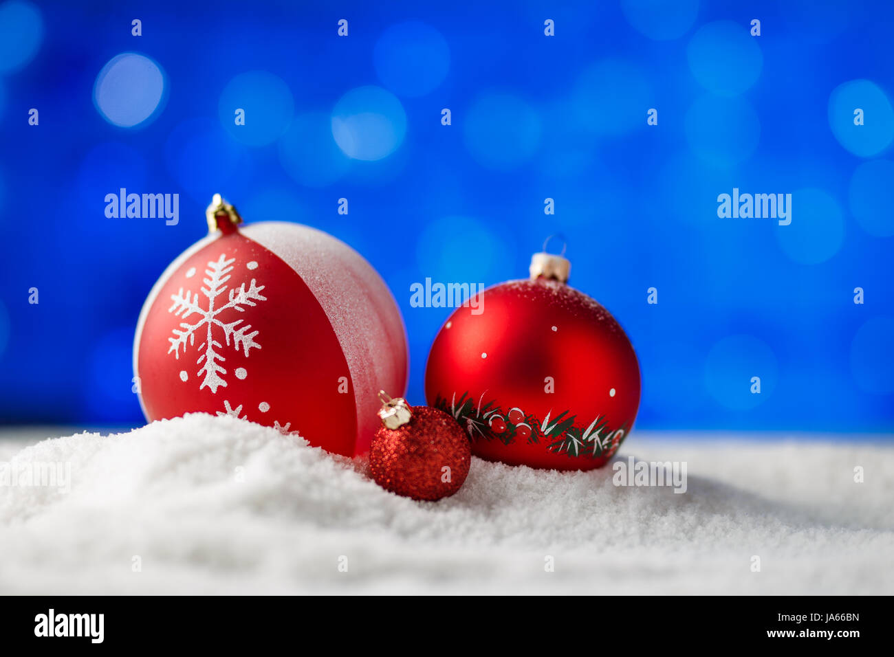 Verzierten Weihnachtskugeln im Schnee mit blauer Hintergrundbeleuchtung. Stockfoto