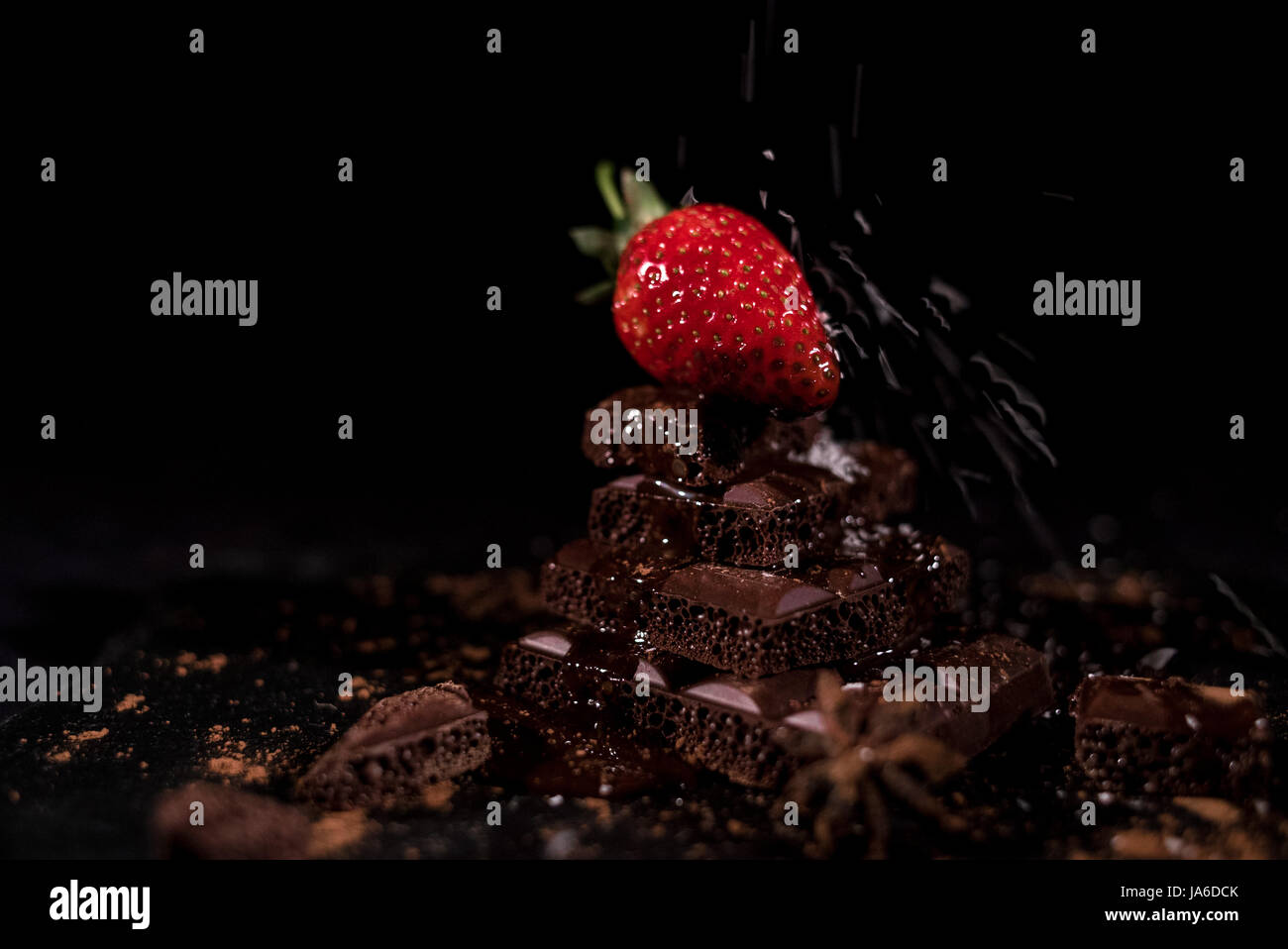 Eine rote Straberry auf eine dunkle Schokolade, zerkleinert. Kokos-chips Stockfoto