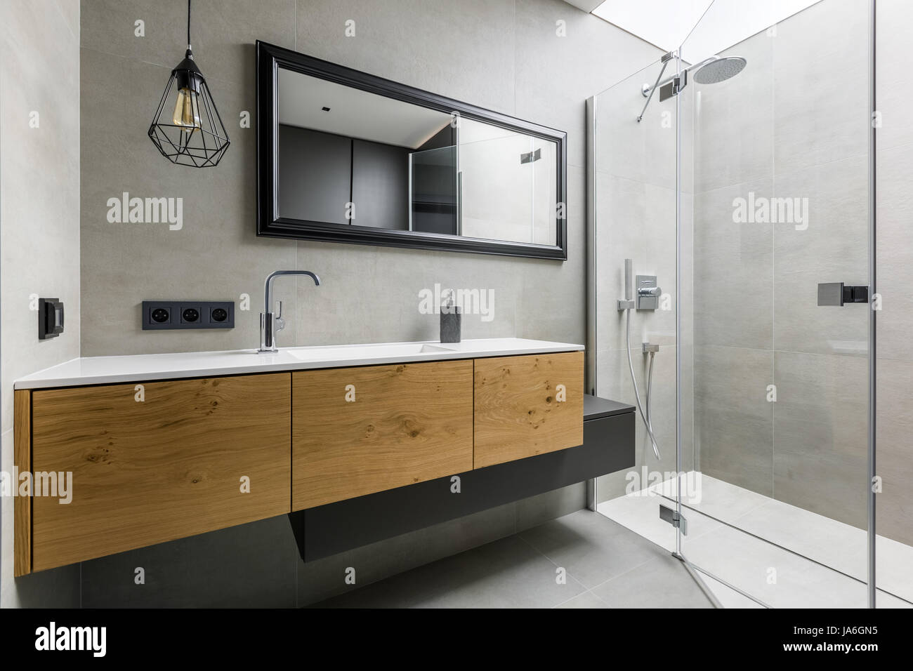 Modernes, graues Badezimmer mit begehbarer Dusche, Spiegel und Arbeitsplatte Becken Stockfoto