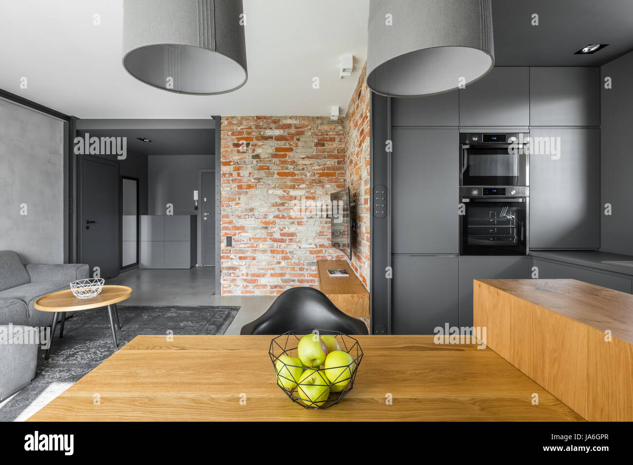 Grau, offenen Plan Wohnung mit modernen, hölzernen Tisch und Lampen Stockfoto