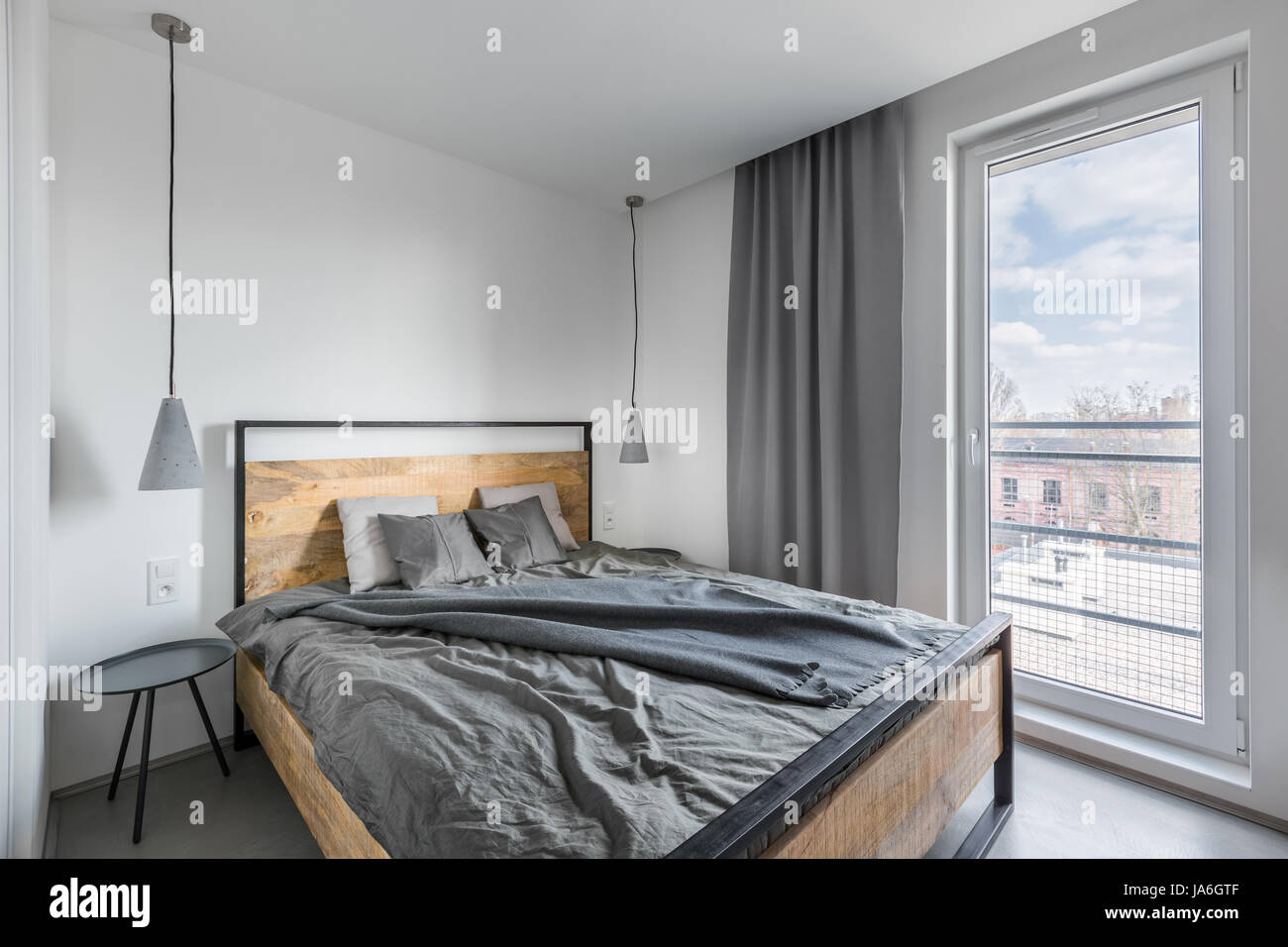 Graue und weiße Schlafzimmer mit Holz-, Doppelbett und Lampen Stockfoto