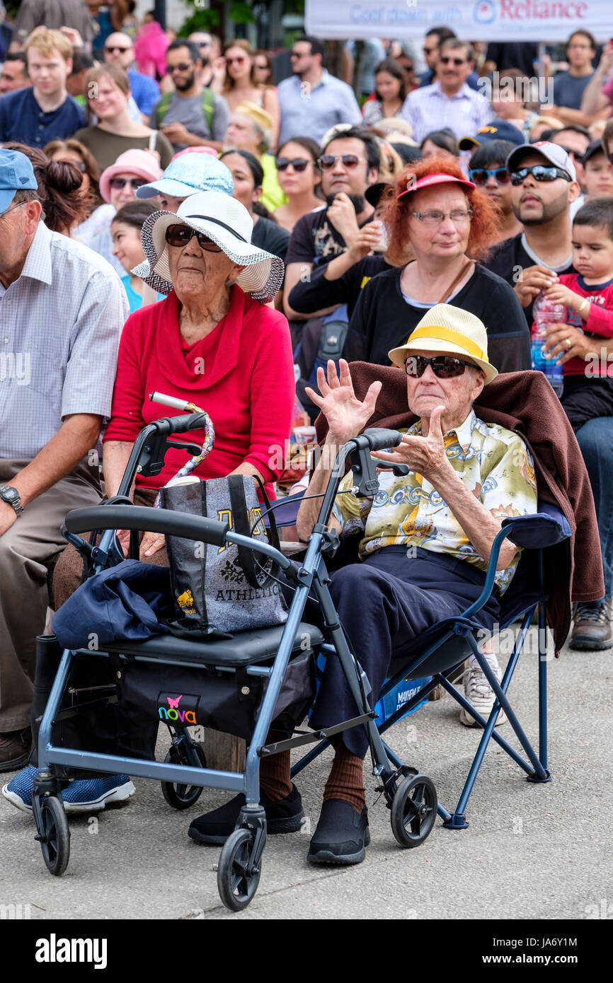 Alter-Paare, die Spaß an einem Musik-Festival, männlichen und weiblichen Senioren tragen Strohhüte und Sonnenbrillen, klatschte beim Klang der Musik, amüsieren, haben Spaß, outdoor-Aktivitäten, Menschenmenge. Stockfoto