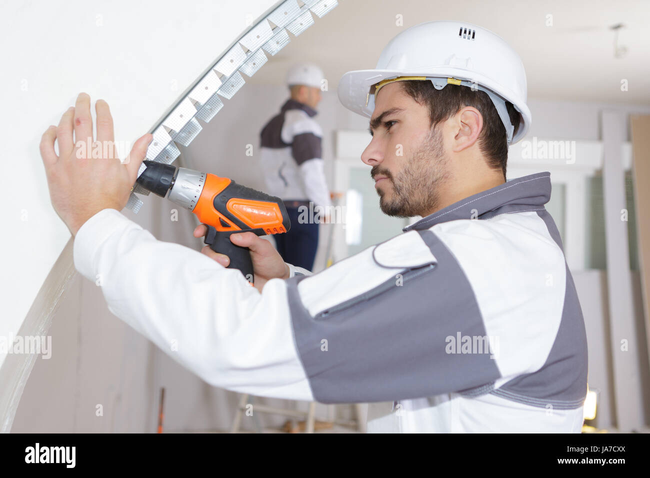 junger Mann Bohren Wand im Innenbereich Stockfoto