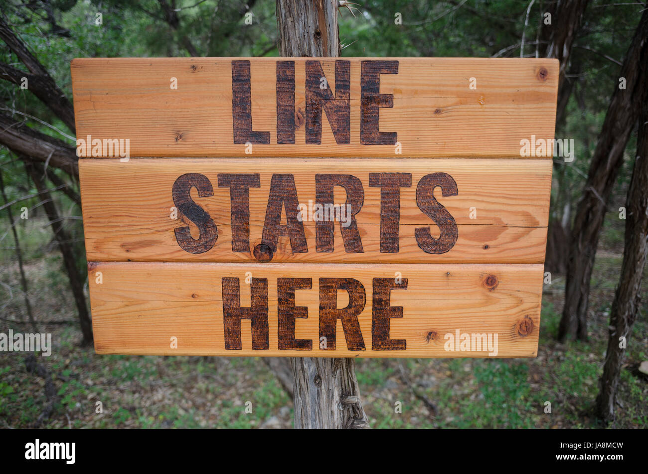 Ein Holzschild, der sagt "Linie hier in Wimberley, Texas beginnt": Stockfoto