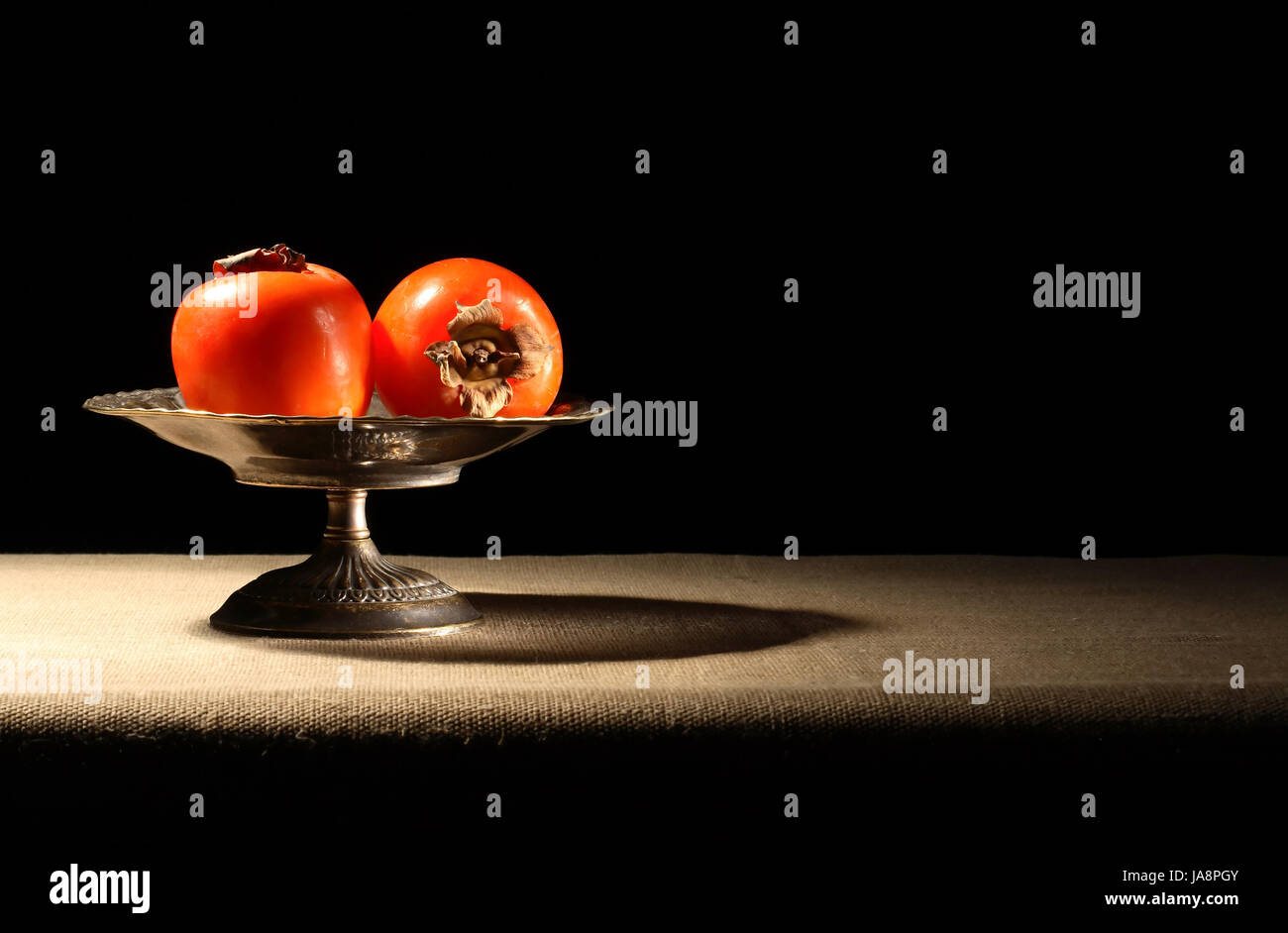 Vintage Messing Schale mit Kaki Früchten auf Leinwand Oberfläche Stockfoto