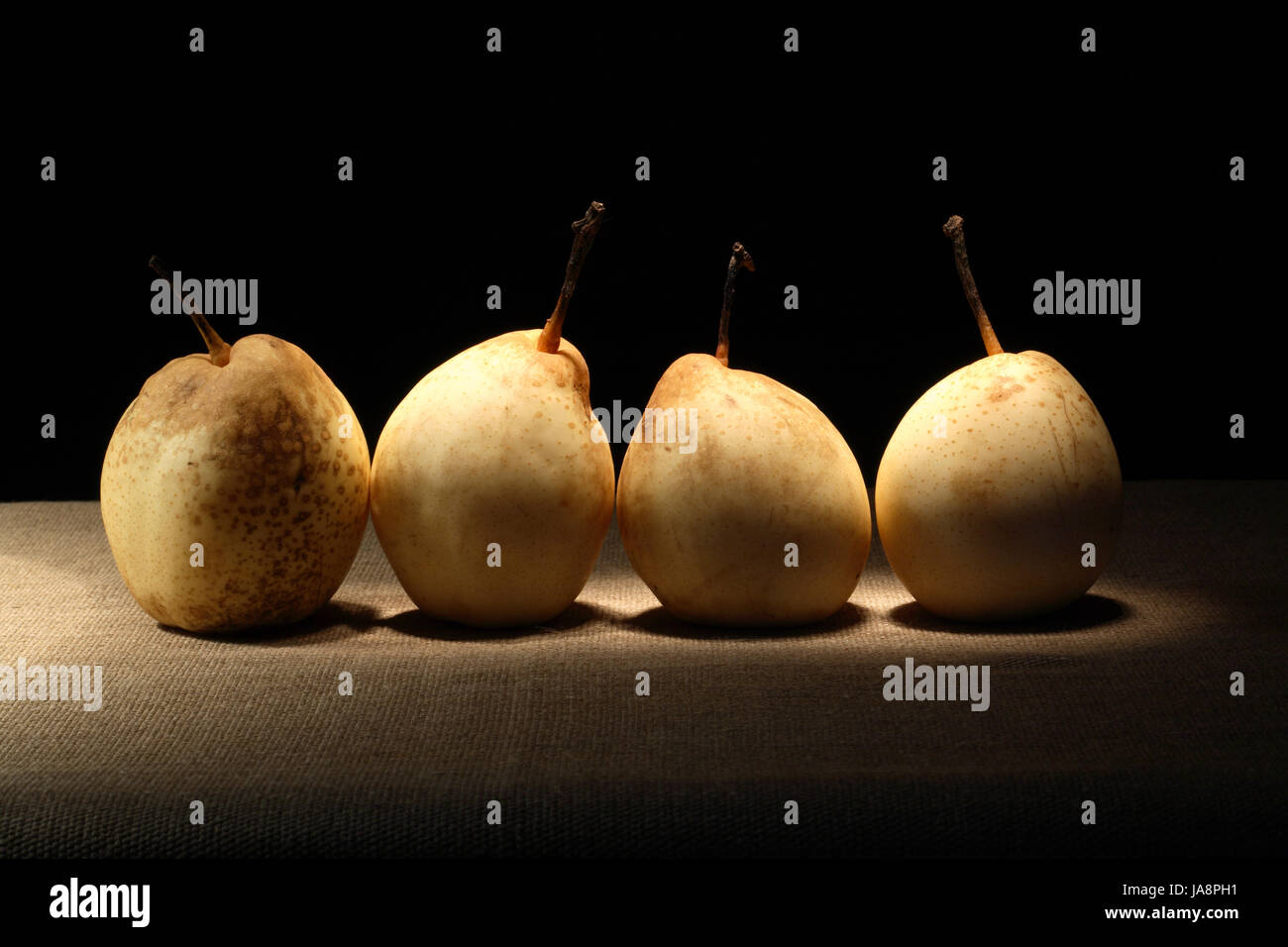 Einige Birnen in einer Reihe auf Leinwand Oberfläche auf dunklem Hintergrund Stockfoto