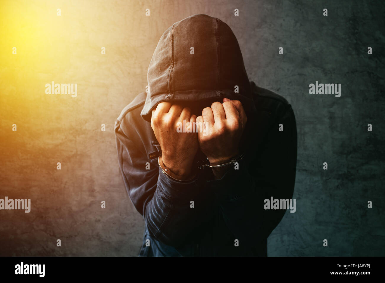 Verhafteten Computer-Hacker und Cyber-kriminellen mit Handschellen tragen Kapuzen Jacke Gesicht versteckt Stockfoto