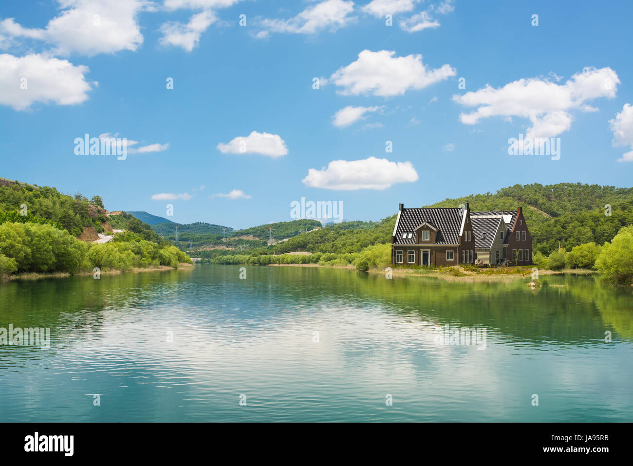 Das Haus am See und frische grüne Natur mit blauem Himmel. Stockfoto