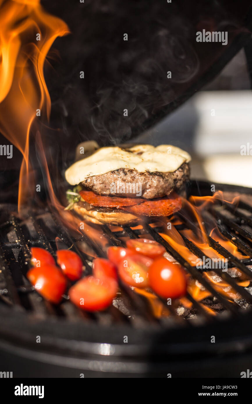 Köstliche Cheeseburger mit Tomaten kochen auf heißen flaming Grill. Grill. Restaurant Stockfoto