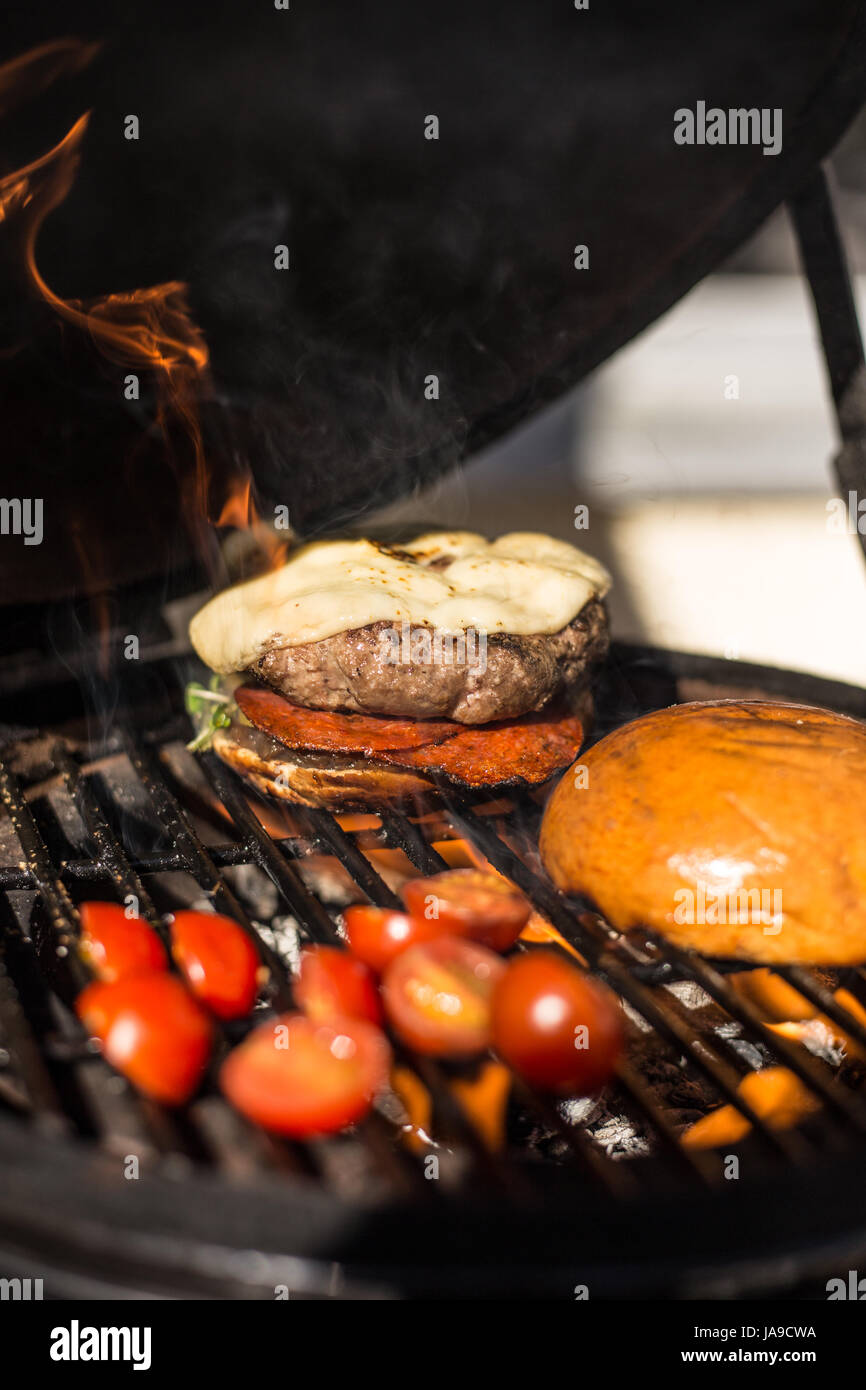 Köstliche Cheeseburger mit Tomaten kochen auf heißen flaming Grill. Grill. Restaurant Stockfoto