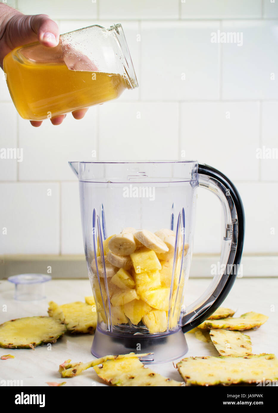 Zugabe von Honig in einem Mixer mit Obst und Wasser Stockfoto